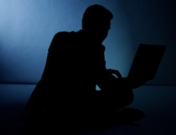 Silhouette of businessman working on laptop. 