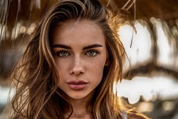 Beauty portrait of gorgeous young blonde caucasian woman with naturl freckles on face. Girl is looking at the camera. Long blonde hair. Delicate makeup. Tanned skin. Summer vibes.