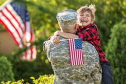 Happy reunion of soldier with family, son hug father with american flag