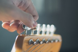 Tuning guitar string by adjusting tuning machines