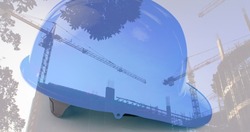 Image of safety helmet over building site and cranes. work and safety concept digitally generated image.