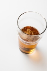 Overhead image of half full pint glass of lager beer, with copy space on white background. Drinking alcohol, refreshment and lager day celebration concept.
