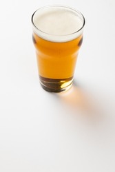 Image of full pint glass of lager beer, with copy space on white background. Drinking alcohol, refreshment and lager day celebration concept.