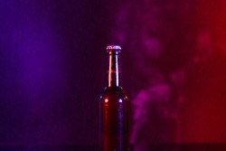 Image of brown glass lager beer bottle with crown cap, with copy space on smokey background. Drinking alcohol, refreshment and lager day celebration concept.