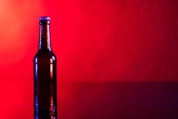 Image of brown glass lager beer bottle with crown cap, with copy space on red background. Drinking alcohol, refreshment and lager day celebration concept.