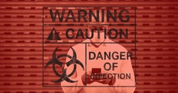 Digital illustration of a warning sign with a hazard sign with warning, caution, danger of infection signs over a man wearing a face mask, standing on a street, using a smartphone in the background.