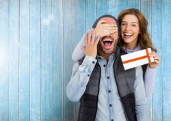 Woman giving surprise gift to man against wooden background