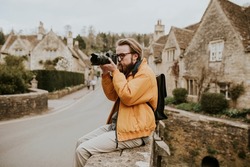 Photographer man taking photos in the village in Cotswolds, UK