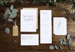 Wedding Invitation Cards Papers Laying on Table Decorate With Leaves