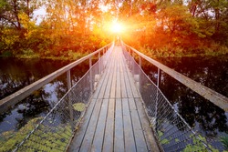 Small bridge over river in forest on sunset background