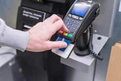 Man paying at the self-service counter entering credit card pin code for security password in credit card swipe machine. shopping time 