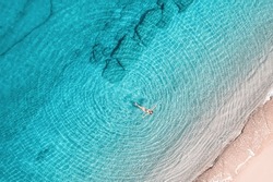 Young woman in a swimsuit swimming in sea water on the beach. View from above. Top, drone view