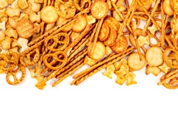 An assortment of salt crackers, sticks, pretzels, and goldfishes, shot from above on a white background with copy space. Salty party snacks mix with a place for text