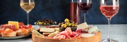 Italian antipasti or Spanish tapas panorama with wine, cold meat and cheese. Rose, white and red wine, a gourmet charcuterie and cheese platter and crostini with parma and salmon