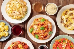 Pasta, many different varieties, overhead flat lay shot. Italian food and drinks, shot from the top. Spaghetti in tomato sauce, mushroom pasta, Bolognese, with wine, on a rustic wooden background