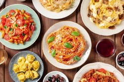 Pasta, many different varieties, overhead flat lay shot. Italian food and drinks, shot from the top. Spaghetti in tomato sauce, mushroom pasta, chicken penne etc, with red wine