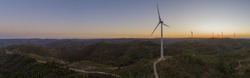 Aerial panoramic Wind farm turbines silhouette at sunset. Clean renewable energy power generating windmills. Algarve countryside. Portugal.
