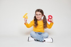 Little Child Girl Playing with Figures, early Education, Mathematics and Numeracy. Cute Girl with glasses sit legs crossed         