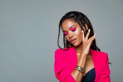 Fashion Portrait Black Woman in Pink stylish jacket. Pink Makeup curly hair and braids. Luxury Fashion model African American posing in studio against a pink wall. Beautiful black woman               