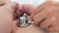 Doctor listens the heart to small newborn with stethoscope. Cute boy and chubby hands of a child. A newborn age of 3 months. Pediatrician's appointment, maternity concept