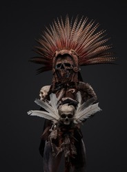 Shot of aztec witch dressed in ceremonial headdress holding staff with skull.