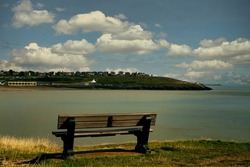bench in the park. Outdoor park view the sea with wooden chair and cloud sky.