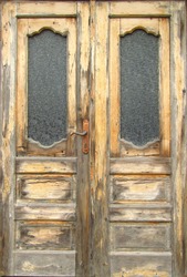 Pattern of old wooden double door with glass panes outside exposed to the weather. Close-up.