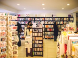 De focused/Blur image of a bookstore with customers reading and looking for books. Toned image. Warm tone. Bookstore background. 