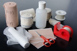 Different rolls of medical bandages and care equipment on a black background