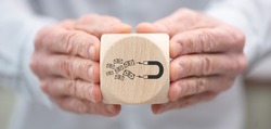 Hand holding a wooden cube with symbol of investors attraction concept