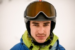 Head shot of handsome man skier wearing ski helmet with goggles on it. Male portrait