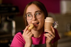 Handsome young woman eats cake macaron. Female portrait with sweet food and drink. Woman drinks coffee and eats dessert