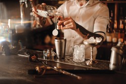 Bartender is adding ingredient in shaker at bar counter