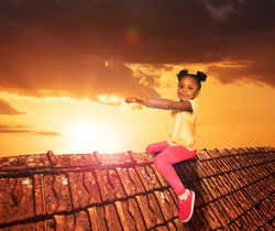 Happy little girl sit on the roof in dream like illustration over sunset