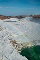 View of Niagara Falls with colorful rainbow from Ontario, Canada towards International crossborder Bridge