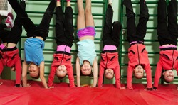 Sporty kids making handstand position in gym