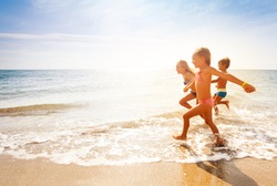 Cute kids having fun on sandy beach in summer