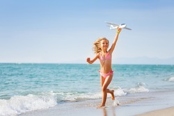 Little girl running with toy plane on the beach