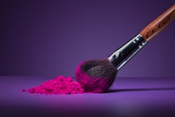 Clouse-up of makeup brush and face powder on purple background