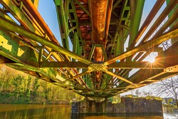 HDR view below a colorful construction of a railway steel bridge with back light of the sun