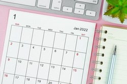 January 2022 calendar sheet with keyboard computer on pink background.