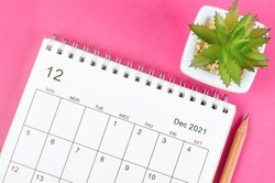 December 2021 desk calendar with pencil on pink background.