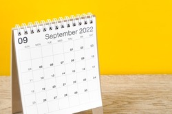 The September 2022 desk calendar on wooden table with yellow background.