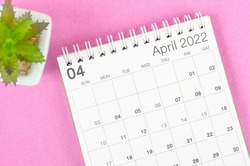 The April 2022 desk calendar with plant pot on pink background.