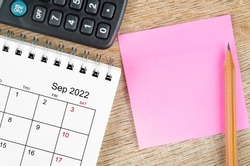 The Blank sticky note on September 2022 desk calendar on wooden background for your text.