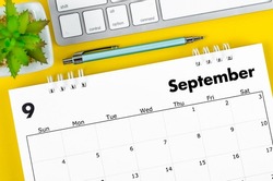 The September 2022 desk calendar with pen and keyboard computer on yellow background.