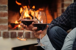 Two glasses of wine in the hands of man and woman on the background of fire