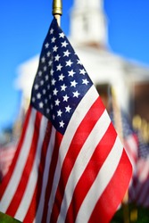 Close up of a miniature US flag from a low angle in front of a memorial chapel