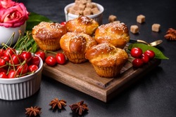 Bunch of freshly baked cherry muffins with fresh berries on a rustic concrete table