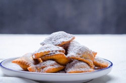 Bugie or ravioli filled with chocolate cream, traditional italian carnival fritters on white plate.

